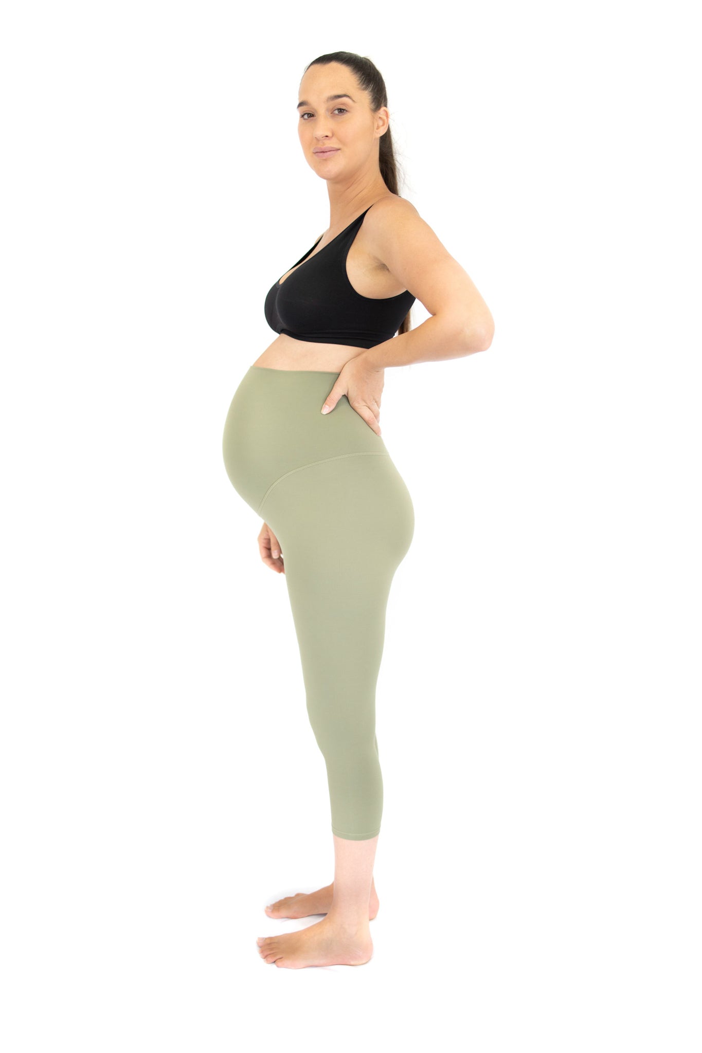 Pregnant woman in black sports bra and light green maternity leggings for comfort