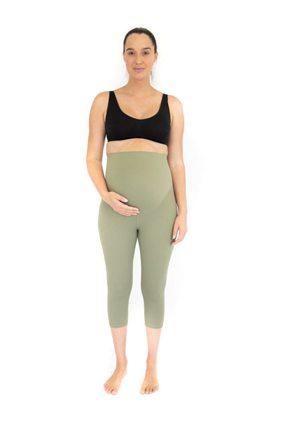 Woman in black sports bra and sage green high-waisted maternity leggings in Olive