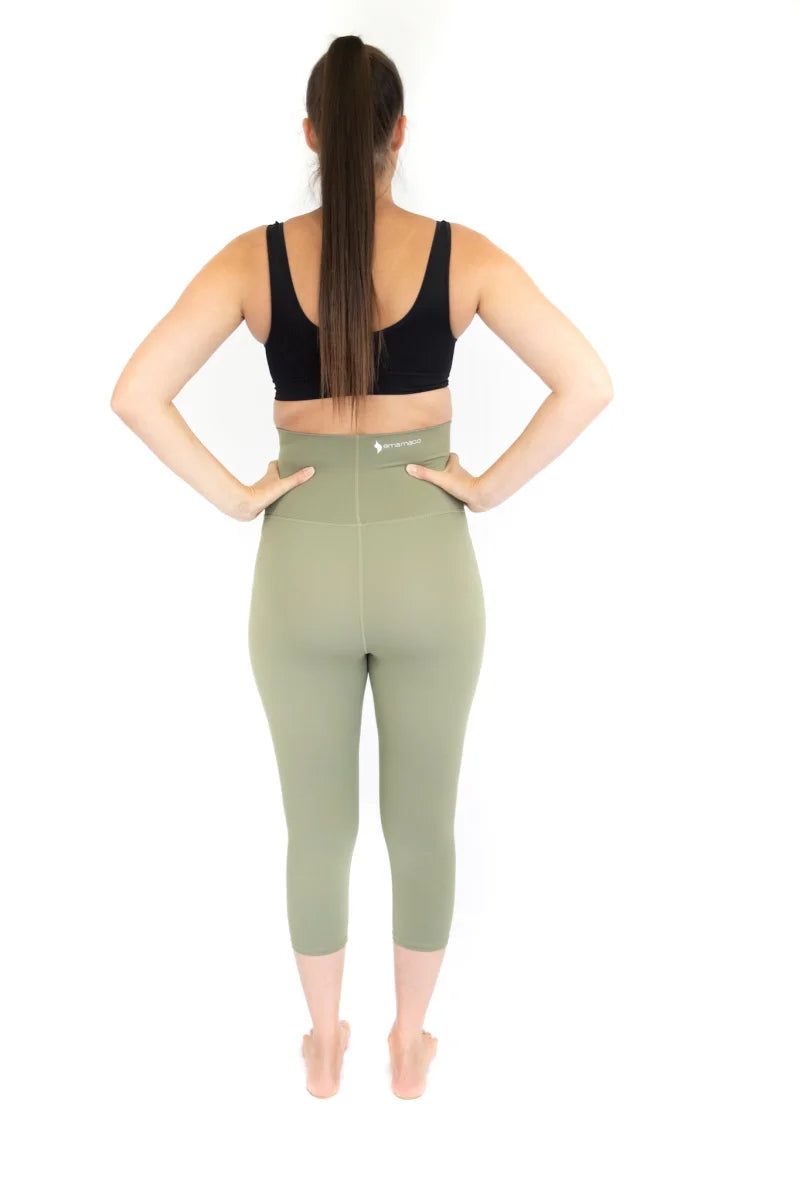 Woman in a black sports bra and light green maternity leggings, showcasing comfort and style