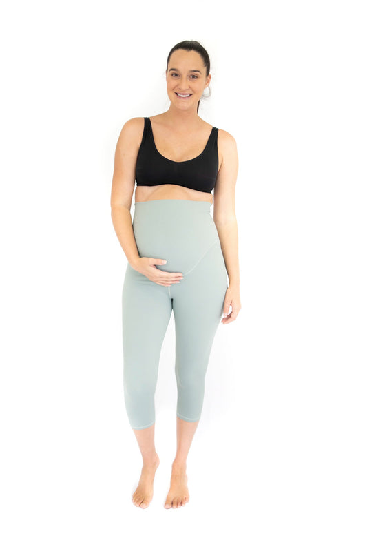 Pregnant woman in black sports bra and blue maternity leggings for active lifestyle