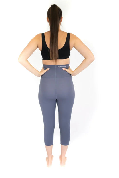 Woman in black sports bra and blue high-waisted maternity leggings viewed from behind