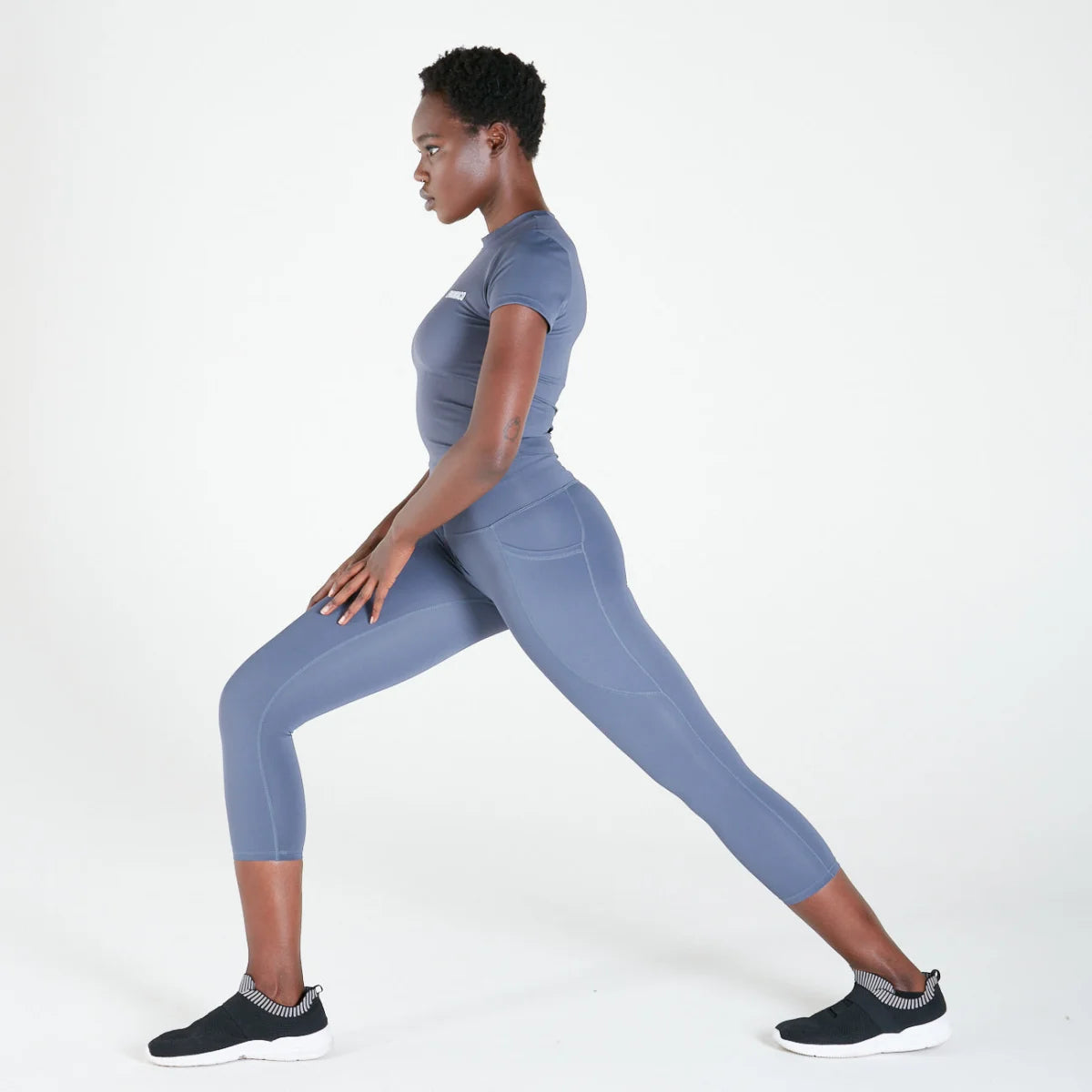 Woman in blue activewear stretching in 3/4 Shaper Move Leggings with pockets