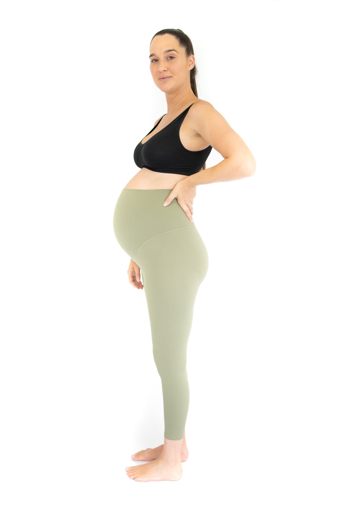 Pregnant woman in black sports bra and olive Emamaco maternity leggings, showcasing style