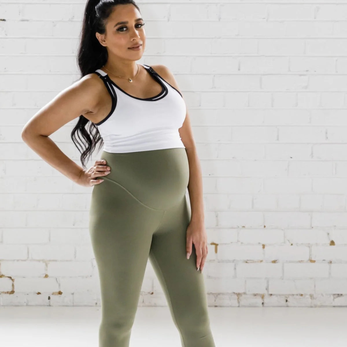 Woman in a white tank top and olive green Emamaco maternity leggings for activewear