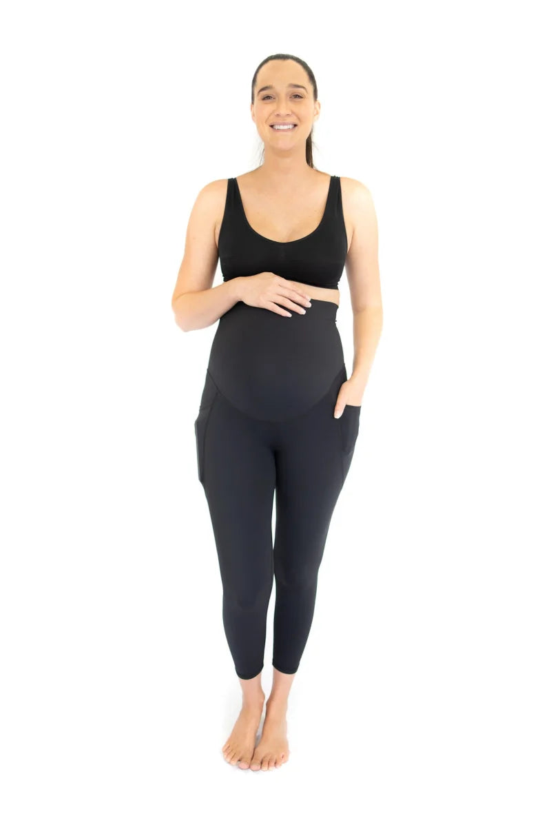 Woman in dark athletic wear showcasing Emamaco maternity leggings with pockets