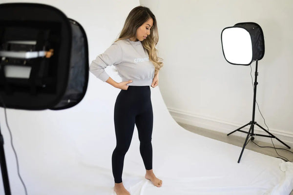 Person in white long sleeves and black leggings modeling Emamaco’s post-pregnancy recovery leggings