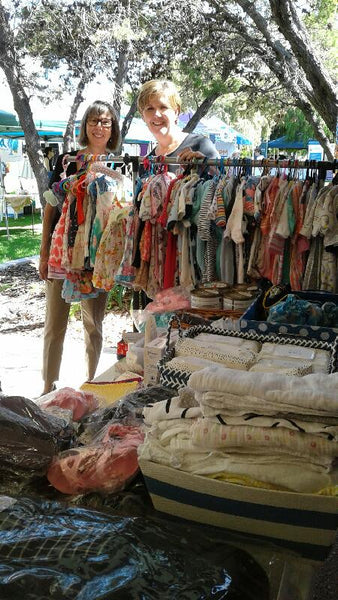 Clothing rack with colorful dresses at an outdoor market for pregnancy assistance Bunbury.