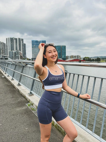 Person in navy blue activewear on waterfront walkway, showcasing Emamaco maternity shapewear.