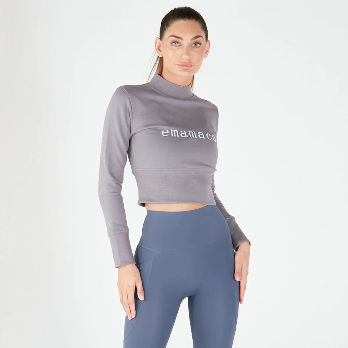 Woman in a crisp charcoal grey cropped long-sleeve top and blue high-waisted leggings