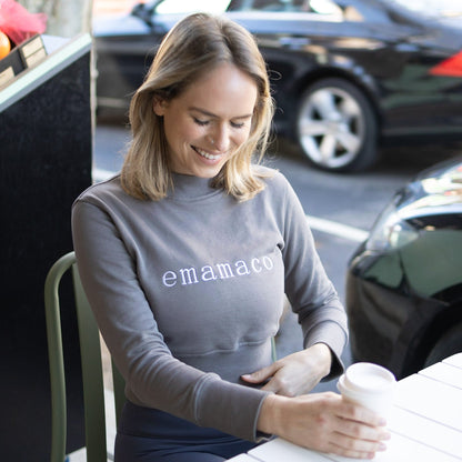 Woman in a crisp charcoal grey sweatshirt featuring emamaco design