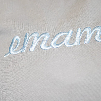 Embroidered cursive text emam on light fabric of cropped sweat maternity activewear