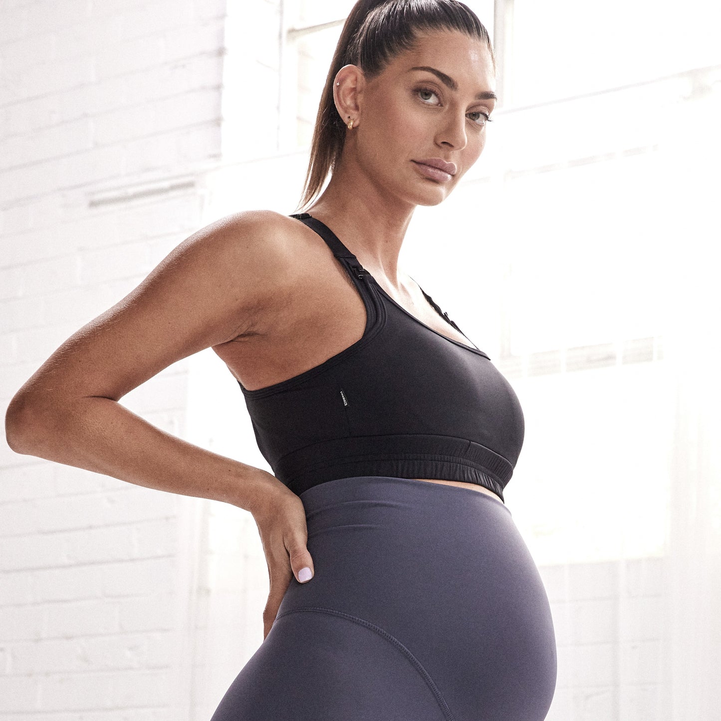 Pregnant woman in athletic wear showcasing Elevate Nursing Sports Bra - Black for active moms