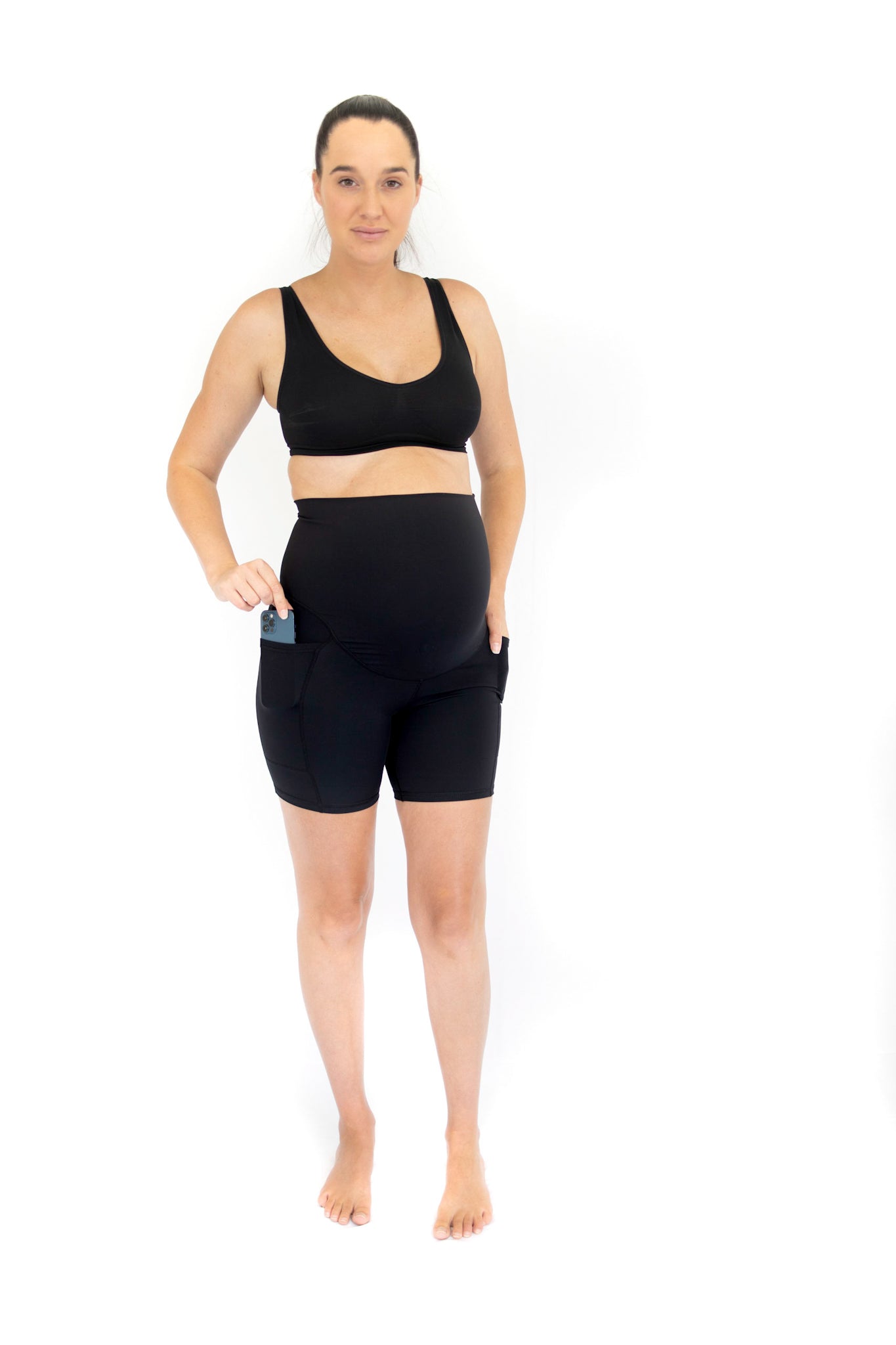 Woman in black Emama Maternity Bike Shorts with pockets, showcasing stylish workout gear