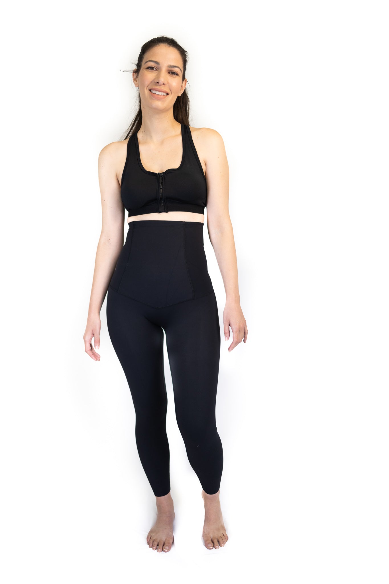 Woman in black sports bra and high-waisted leggings for pregnancy recovery and post partum