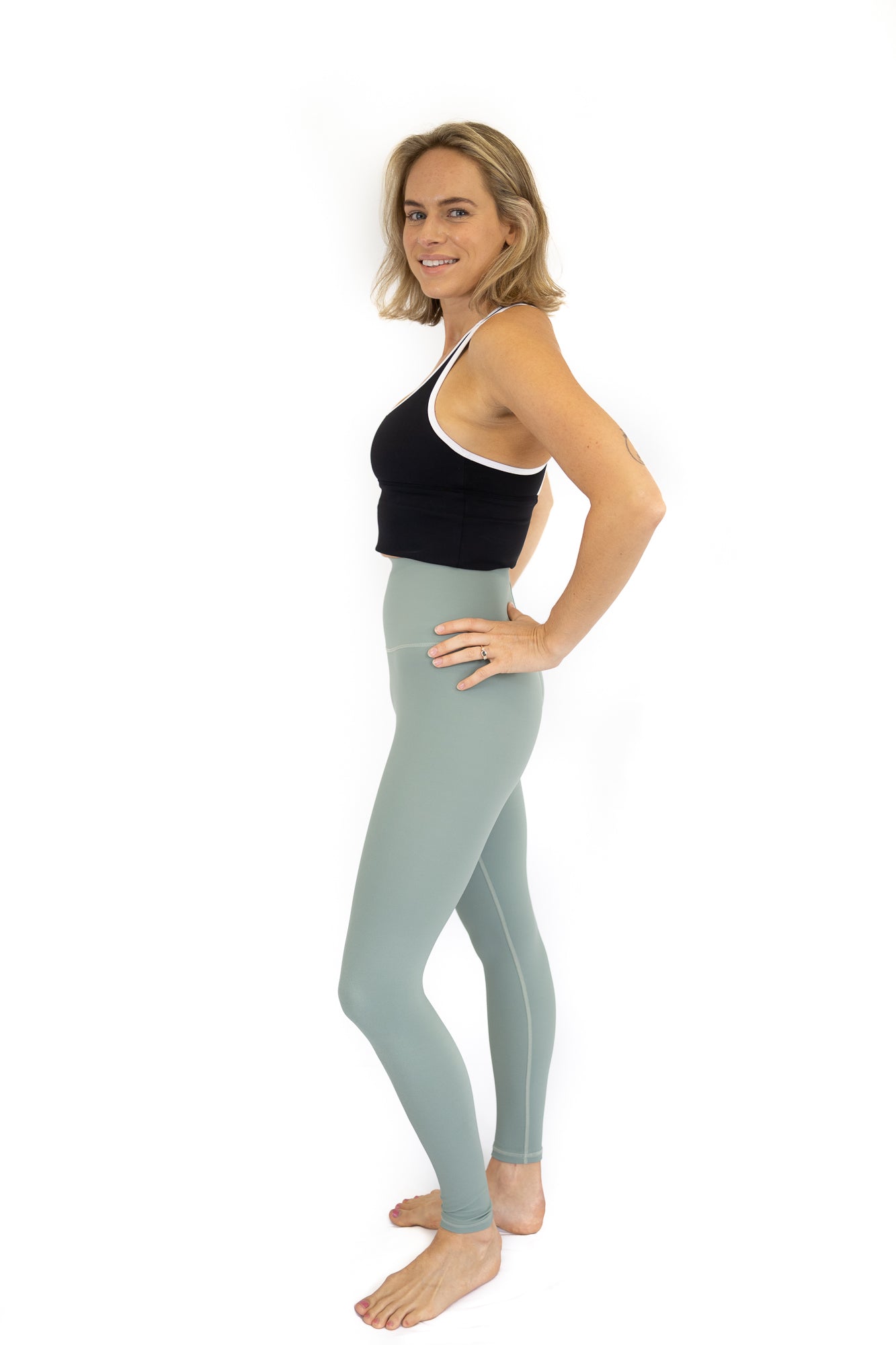 Woman in black tank top and blue leggings modeling Shaper Move activewear for maternity