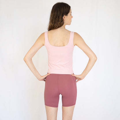 Woman in pink tank top and mauve shorts, perfect for Emamaco Everyday at yoga studio