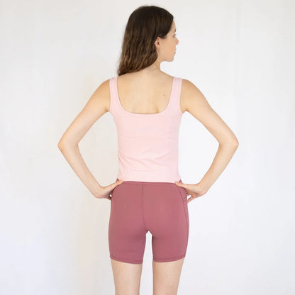 Woman in pink tank top and mauve shorts, perfect for Emamaco Everyday at yoga studio