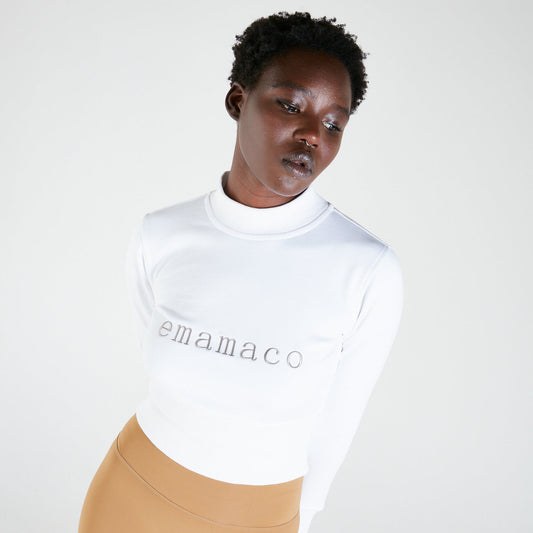 Person in snowiest white turtleneck sweater with delicately stitched emamaco logo