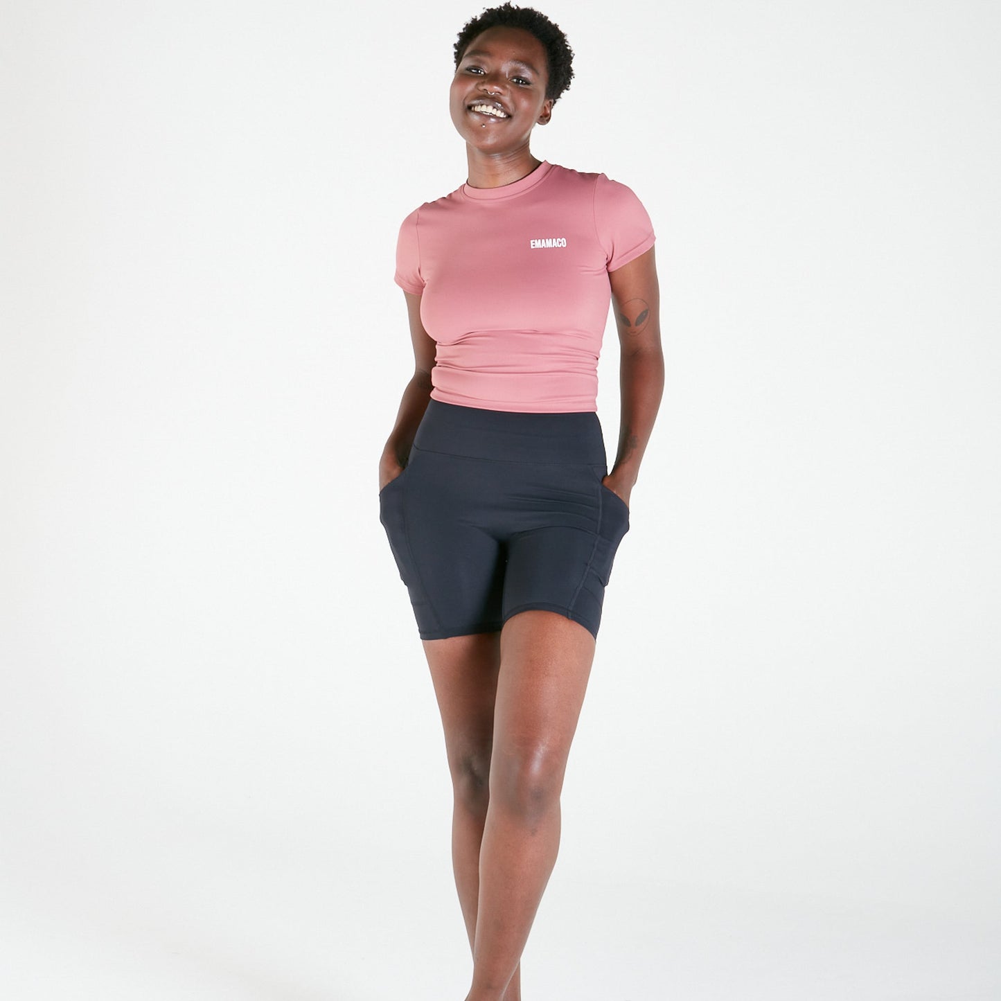 Smiling person in pink crop top models Vibe Shorts with regular fit waistband against white background